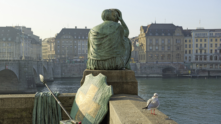 Nachdenkliche Helvetia-Statue mit abgelegtem Schild und Speer mit Blick auf den Rhein in Kleinbasel